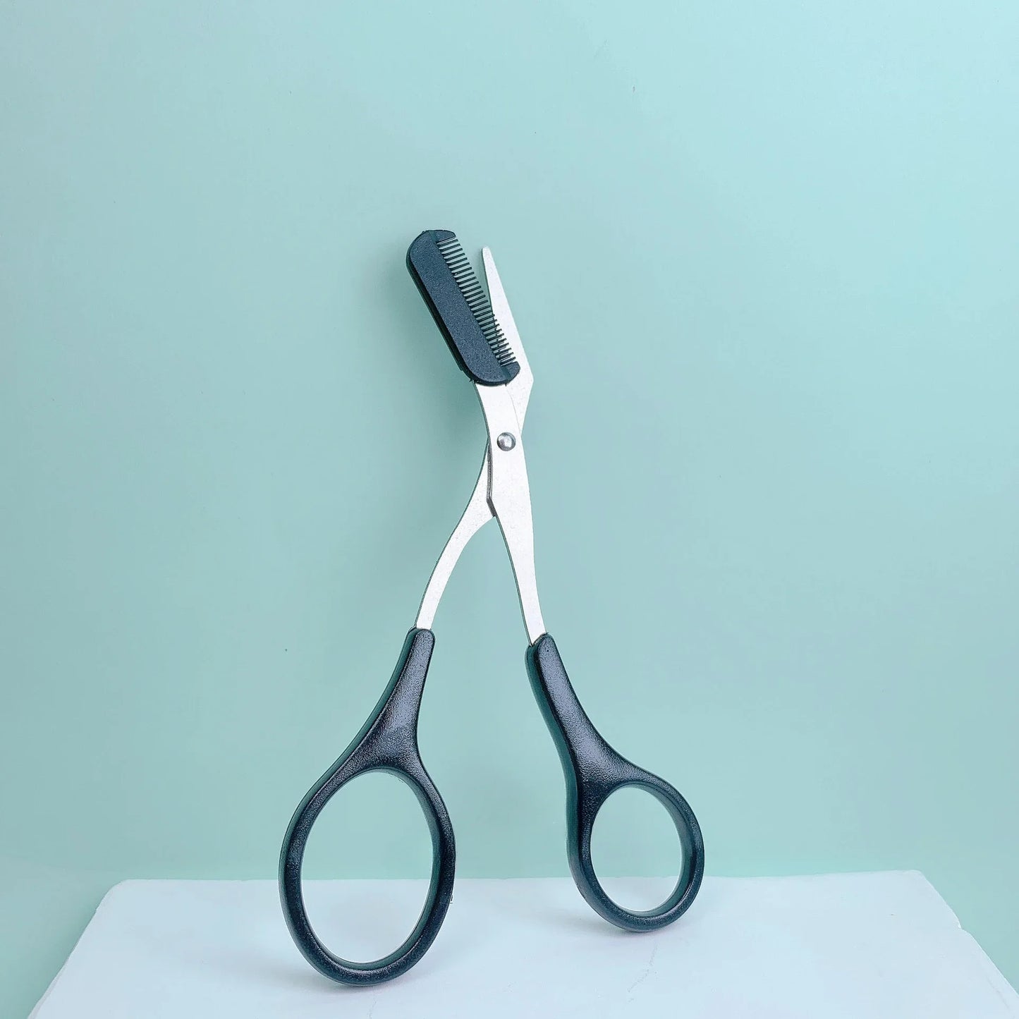 Eyebrow Trimming Scissors with Built-in Comb on a light background, designed for precise eyebrow grooming and trimming.