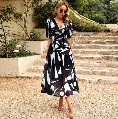 A woman wearing a Summer V-Neck Printed Maxi Dress with a geometric pattern, walking on a garden path.