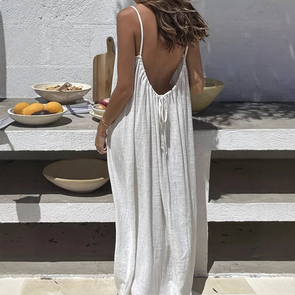 Woman wearing an Elegant Backless Maxi Evening Dress in white, showcasing the open back design at a stylish outdoor setting.