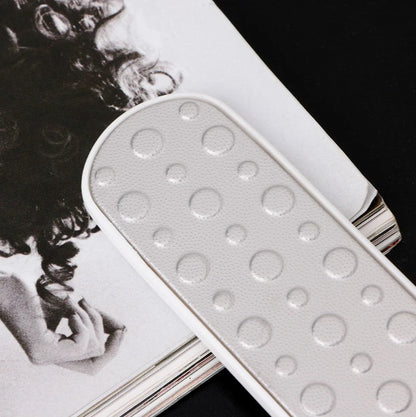 Double-Sided Foot Callus Remover Tool resting on a magazine page, showcasing its textured surface for effective foot care.