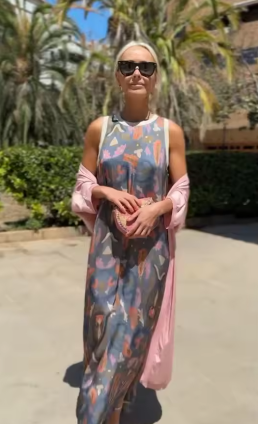 Long printed dress set with matching cardigan showcased on a model walking outdoors in sunny weather.
