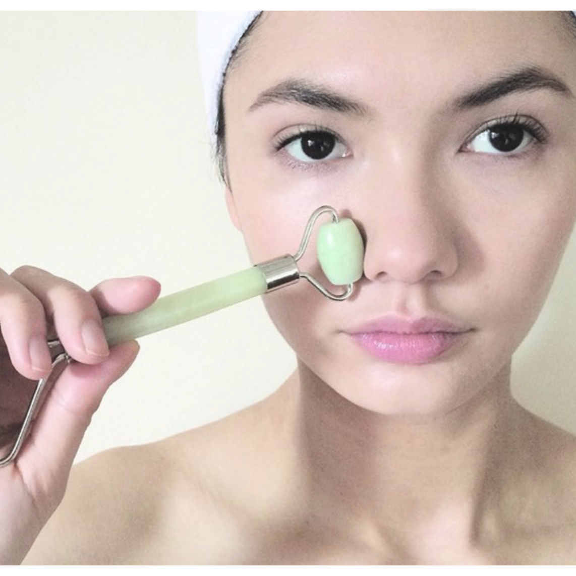 Woman using a Double Head Jade Face Massage Roller for skincare and facial relaxation.