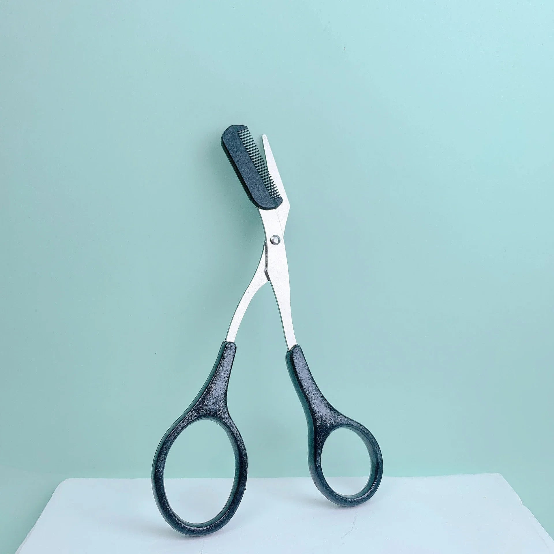 Eyebrow Trimming Scissors with Built-in Comb on a light background, designed for precise eyebrow grooming and trimming.