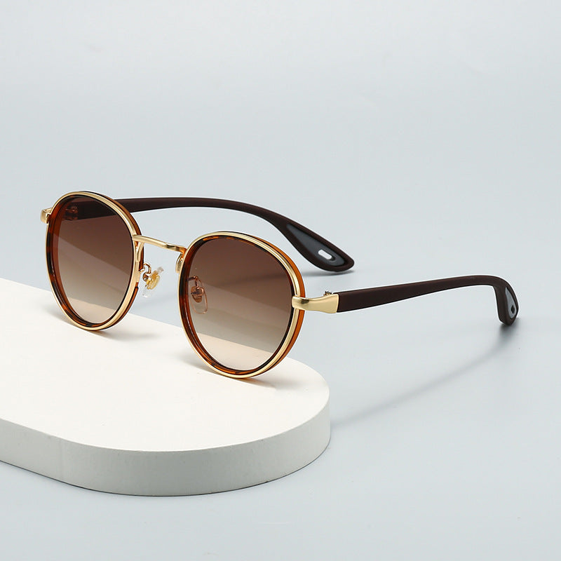 Vintage designer outdoor sunglasses with brown gradient lenses and gold accents on a light background.