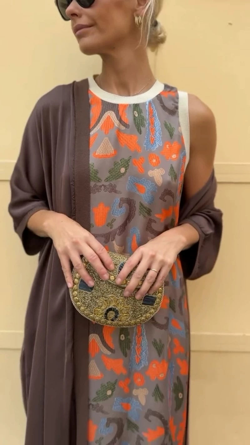 Long printed dress set with matching cardigan worn by a woman with stylish accessories.