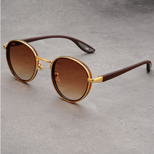 Vintage designer outdoor sunglasses with golden frames and brown lenses on a gray background.
