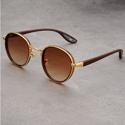 Vintage designer outdoor sunglasses with golden frames and brown lenses on a gray background.