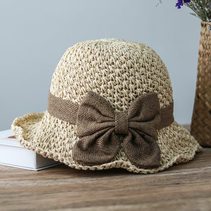 Vintage Foldable Straw Sun Hat with Wide Brim Bow on a wooden table, perfect for summer outdoor activities.