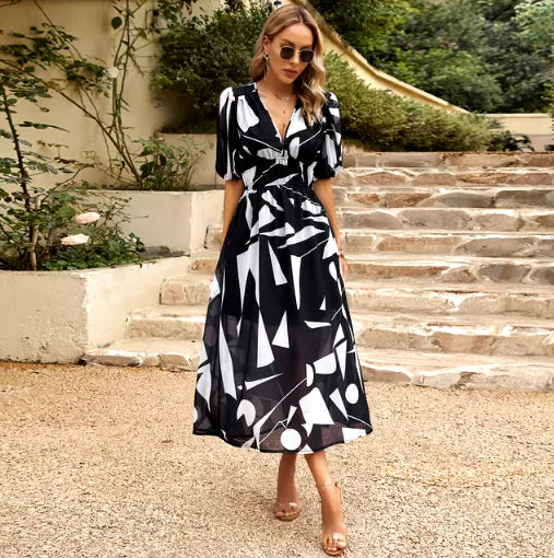 Woman wearing a Summer V-Neck Printed Maxi Dress with geometric patterns, enjoying a sunny day outdoors.